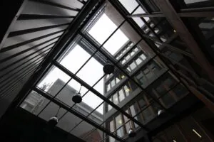 Blik omhoog vanuit een overdekte binnenplaats naar de gevels van moderne gebouwen aan de De Ruijterkade.